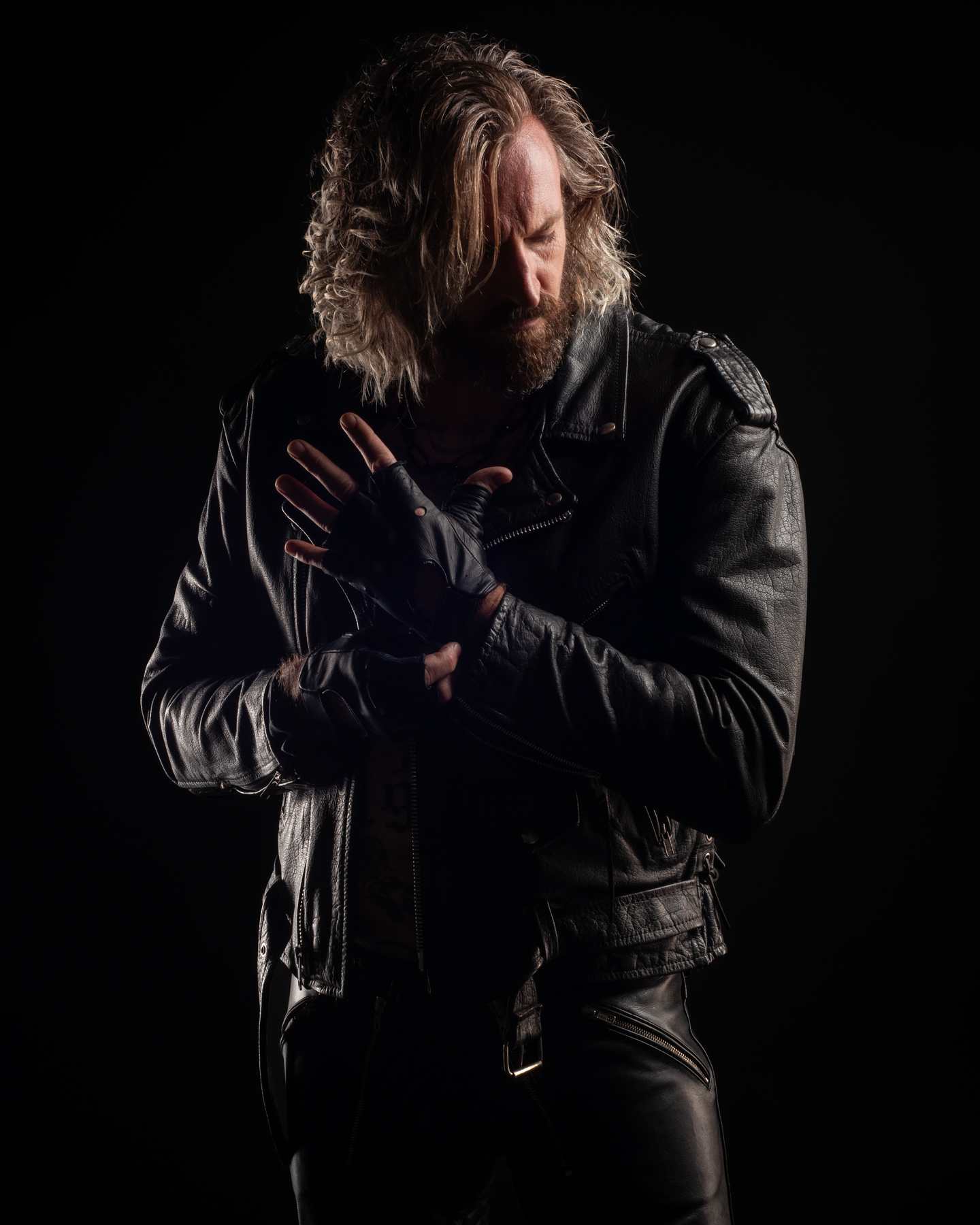 Kevin in a black leather jacket, direct gaze, low light